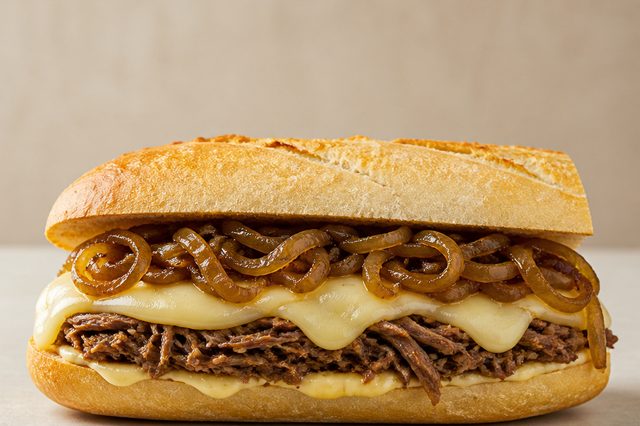 Baguete de carne de panela com cebola caramelizada e queijo